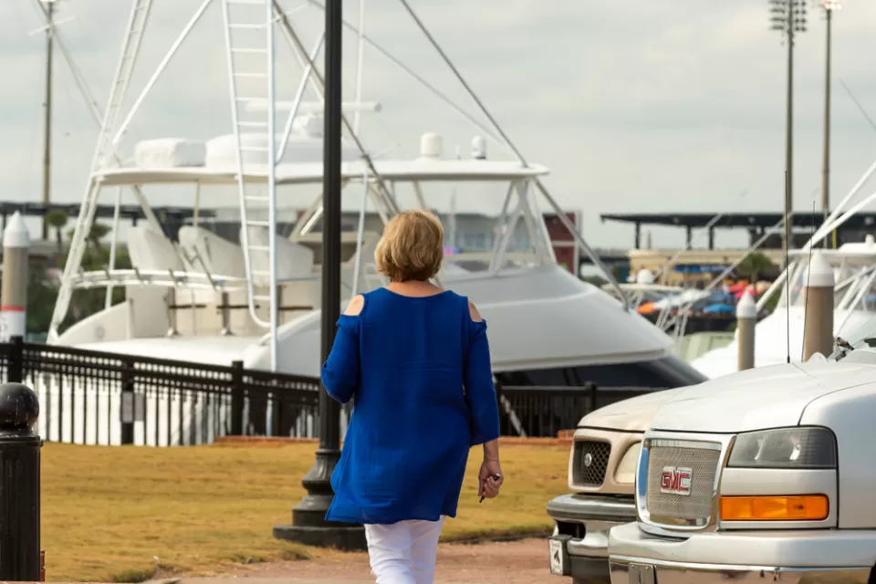 Woman walking at marina in Pensacola, FL with boat in background